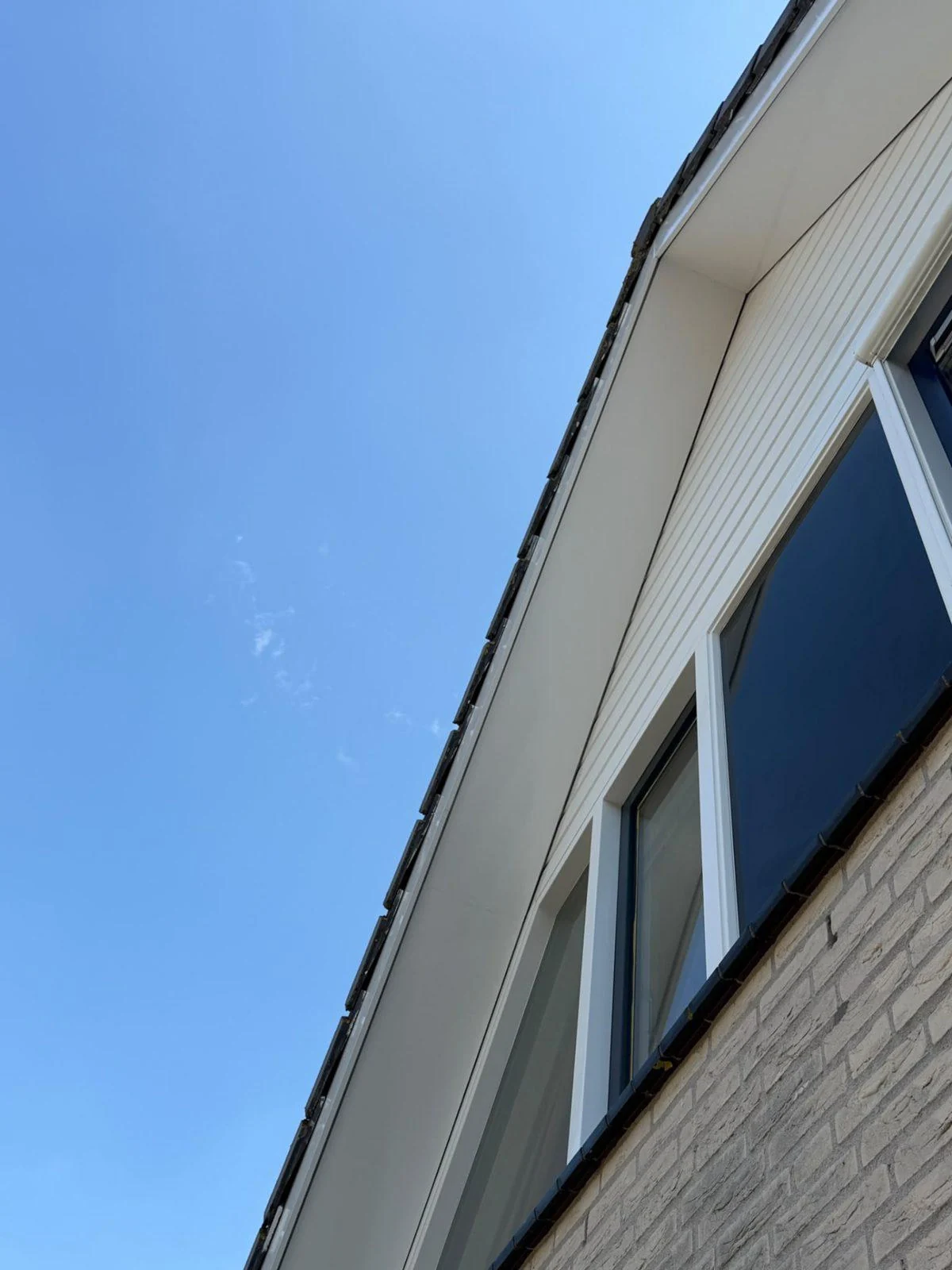 Wit geschilderde boeidelen en kozijnen onder een strakblauwe lucht