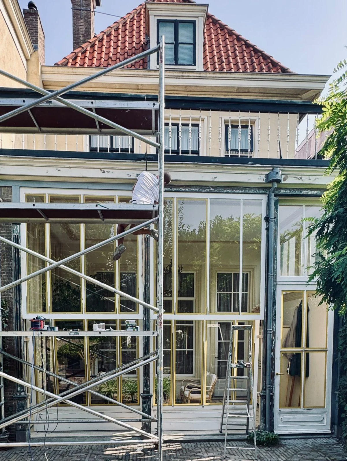 Serre aan een herenhuis met steiger voor schilderwerk aan kozijnen